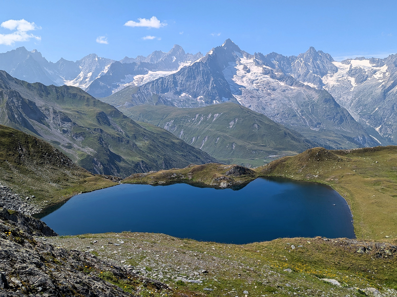 Temné jezero a zasněžené vrcholy v sedle Col du Grand Ferret